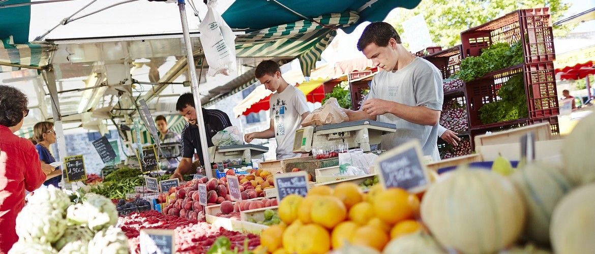 un étal de fruits sur un marché, avec les vendeurs