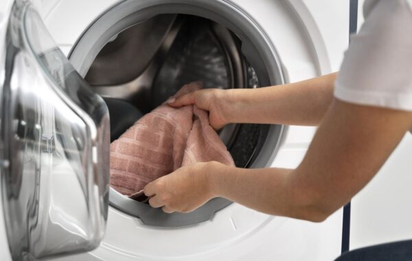 avant-bras d'une personne introduisant du linge dans une machine à laver